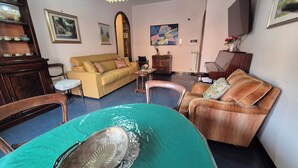Un salon comprenant un canapé, des fauteuils, une table basse et une table à manger.