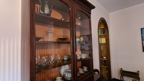 Un coin repas agrémenté d’un buffet en bois où sont exposés des verres et de la porcelaine.