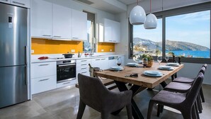 Eine moderne Küche mit einem Edelstahlkühlschrank, weißen Schränken und einem Holzespeisetisch, gedeckt für sechs Personen.