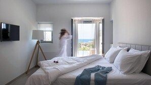 Ein modernes Hotelzimmer mit Bett, Fernseher, einem Fenster mit Vorhängen und Balkonblick.