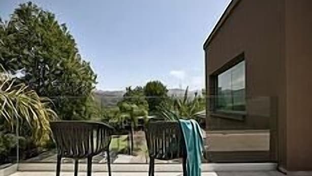 A modern building with a large glass window and a patio area with two chairs. - Luxury 6 bedroom villa   private heated pool with Free Shuttle Service + Free Mini Vans Hire (Alikianos)