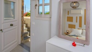 Une chambre à coucher avec un grand miroir, une table de chevet avec une lampe et une fenêtre donnant sur l’extérieur.