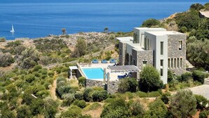 A modern villa with a pool, stone architecture, and a view of the sea. - Villa Queen with a heated pool (Elounda)