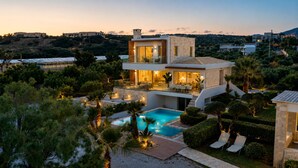 Eine moderne Villa mit Swimmingpool, Sitzgelegenheiten im Freien und Blick auf die umliegende Landschaft.
