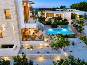 Eine moderne Villa mit Pool, Sitzgelegenheit im Freien und Meerblick.