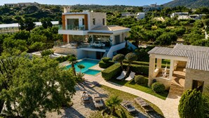 Ein modernes, zweistöckiges Haus mit Swimmingpool, Außenbereich zum Sitzen und Blick auf die umliegende Landschaft.