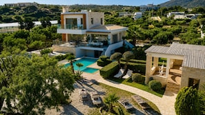 Une maison moderne à deux étages, dotée d’une piscine, d’un espace extérieur aménagé et offrant une vue sur le paysage environnant.