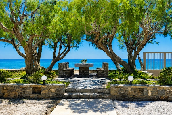 A stone pathway leading to a seating area with a view of the sea.