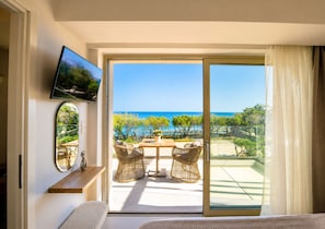 A balcony with a view of the sea, wicker furniture, a flat-screen TV, and a mirror.