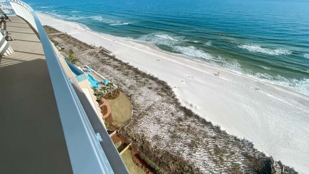 A beach view from a balcony with a pool and a thatched roof structure. - La Playa 1101 Luxury Perdido Key Condo, Breathtaking Views (Pensacola)