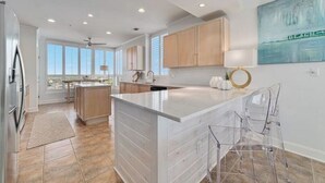 A modern kitchen with a large island, wooden cabinets, and a view to the outside. - La Playa 1101 Luxury Perdido Key Condo, Breathtaking Views (Pensacola)