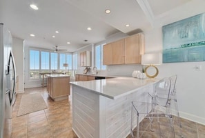 A modern kitchen with a large island, wooden cabinets, and a view to the outside. - La Playa 1101 Luxury Perdido Key Condo, Breathtaking Views (Pensacola)