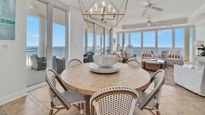 A spacious dining area with a round table, wicker chairs, and a modern chandelier. - La Playa 1101 Luxury Perdido Key Condo, Breathtaking Views (Pensacola)