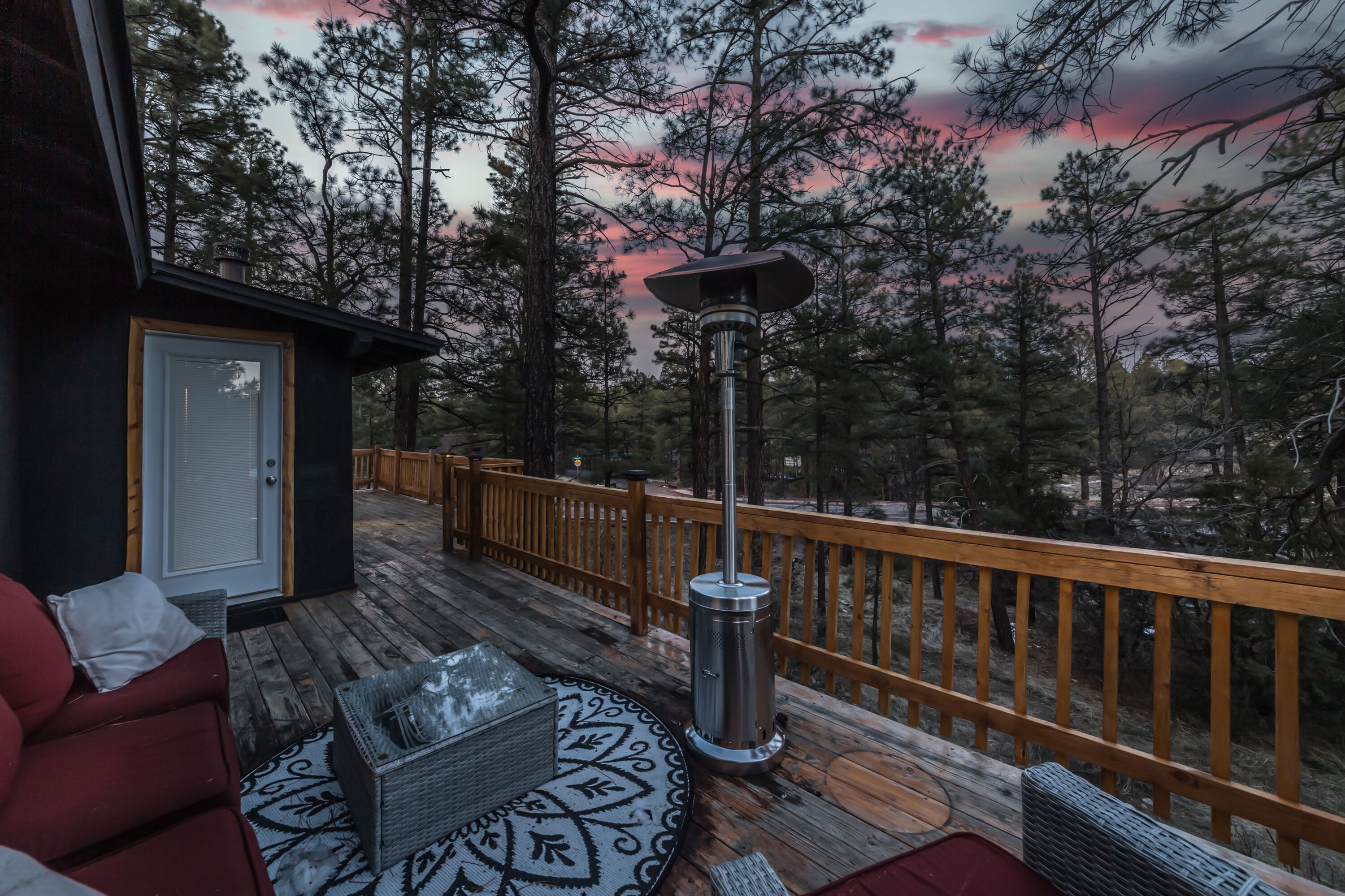 A wooden deck with a metal heater, a red sofa, and a patterned rug.