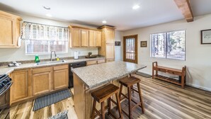 Una cocina con gabinetes de madera, encimera de granito y una isla integrada con taburetes.