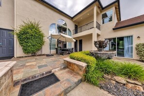 A spacious outdoor patio with a stone floor, a dining area, and a large planter.