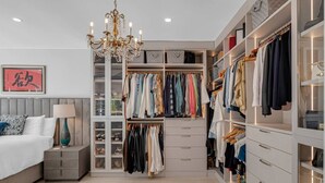 A walk-in closet with multiple shelves and drawers, a chandelier, and a bed with a nightstand. - Casa la Miami, Centrally Located w/ Pool & Gym (Miami)