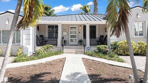A two-story house with a front porch, palm trees, and a clear sky. - Casa la Miami, Centrally Located w/ Pool & Gym (Miami)