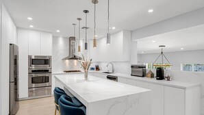 A modern kitchen with built-in appliances, a marble island, and pendant lighting. - Casa la Miami, Centrally Located w/ Pool & Gym (Miami)
