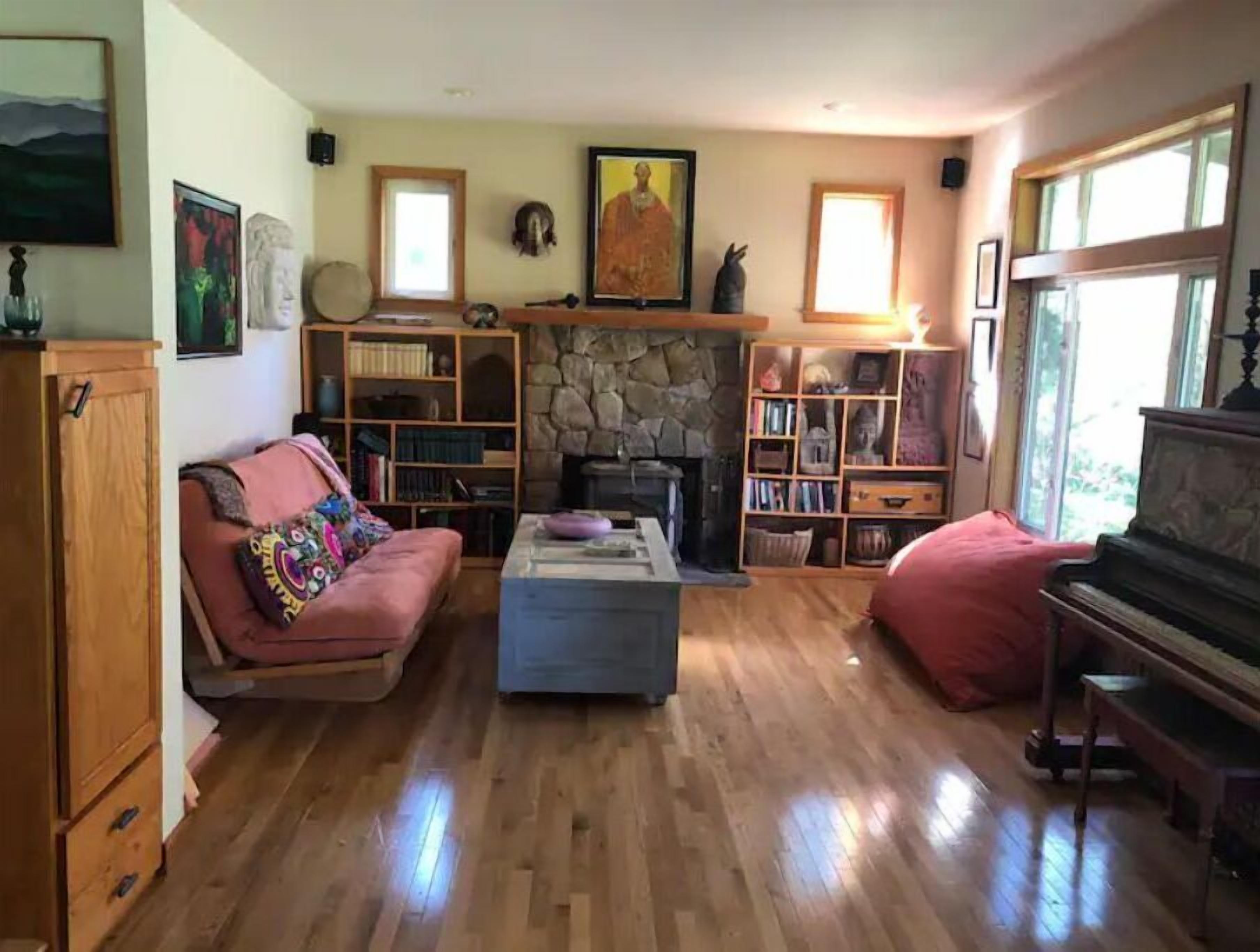 Ein gemütliches Wohnzimmer mit Kamin, Bücherregalen, einem Klavier und einer Couch.