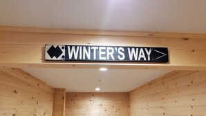 Puinen mökki sisältä, ja seinällä on kyltti, jossa lukee ”WINTER’S WAY”, ja kyltti osoittaa oikealle.