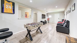 A spacious living area with a foosball table, a sofa, and a basketball jersey on the wall. - The Ultimate Man Cave Haven: Arcade Room/ Pool Table (Houston)