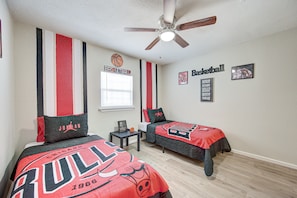 A basketball-themed bedroom with two beds, a ceiling fan, and a window with blinds. - The Ultimate Man Cave Haven: Arcade Room/ Pool Table (Houston)