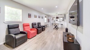 A hotel lobby with a row of leather chairs, a television mounted on the wall, and a reception desk in the background. - The Ultimate Man Cave Haven: Arcade Room/ Pool Table (Houston)
