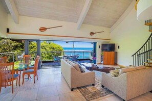 A spacious living area with a balcony overlooking the sea, furnished with sofas, a dining table, and chairs. - Luxury 2-Story Oceanfront Condo w/ Views & Pool (Wailua)