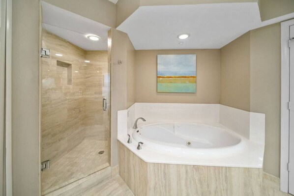 A modern bathroom with a walk-in shower, a freestanding bathtub, and a painting on the wall.