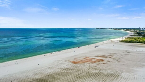 Une plage aux eaux turquoise et limpides, bordée d’un rivage sablonneux.