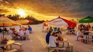 Un espace extérieur aménagé avec des tables rondes et des parasols, le tout mis en valeur par le décor d'un coucher de soleil.
