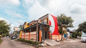 Un edificio con un letrero grande rojo y blanco, un balcón y un camino de entrada pavimentado.