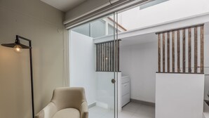 Een moderne kamer met een schuifdeur naar een balkon, een beige fauteuil en een minimalistisch design.