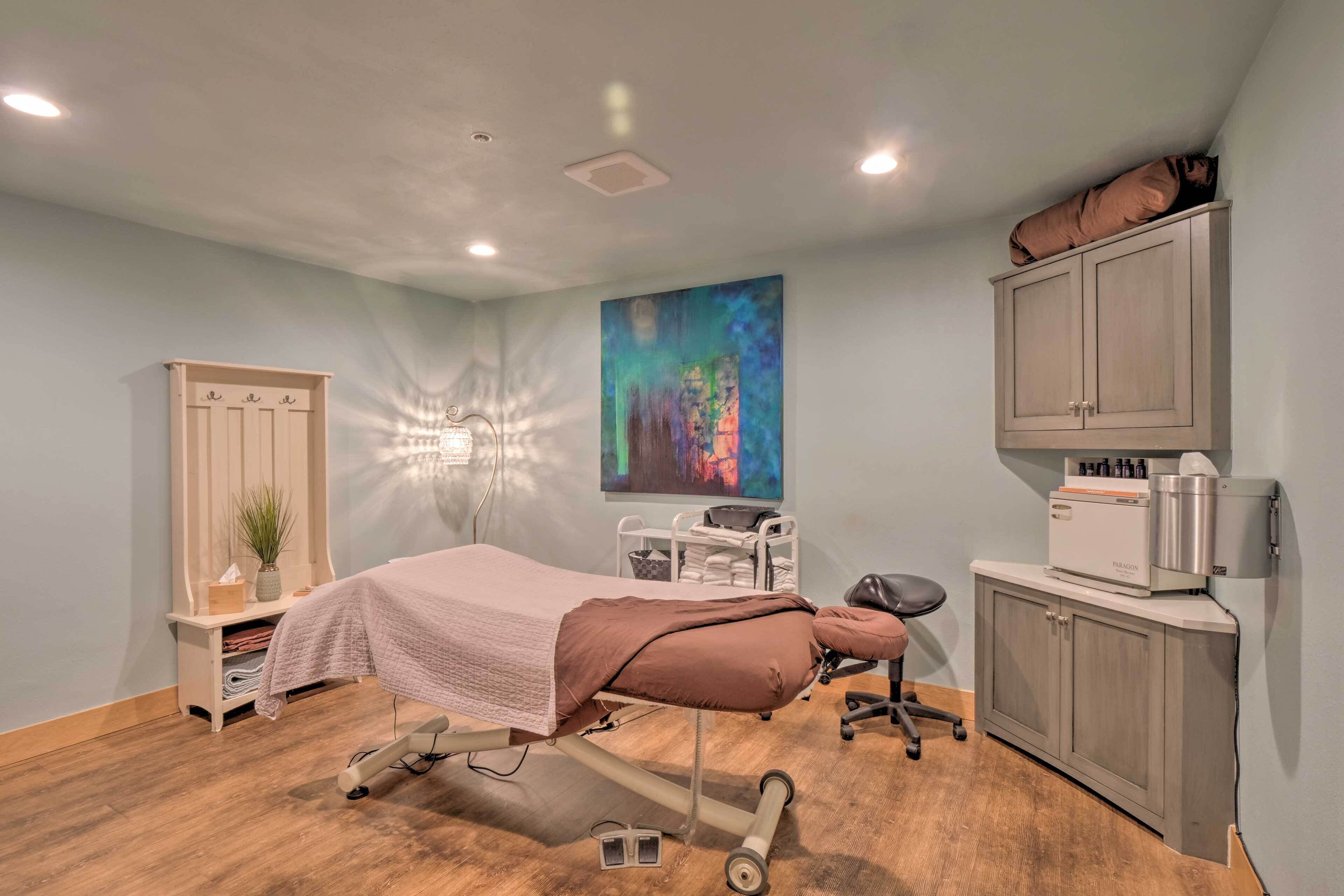 A medical examination room with a bed, examination table, cabinets, and a wall-mounted medical device.