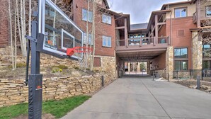 A basketball court with a hoop, a stone wall, and a building with balconies and large windows. - Fabulous Grand Timber Lodge Ski In and Ski Out Resort in Breckenridge (Breckenridge)