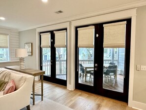 Una habitación con sofá, una mesa y vistas a un patio exterior con mesa y sillas.