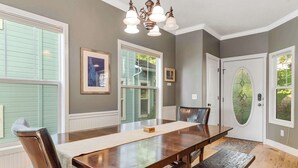 A dining room with a large wooden table, chairs, and a chandelier.