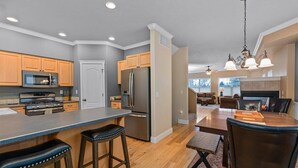 A modern kitchen with a central island, wooden cabinets, stainless steel appliances, and a dining area with a fireplace.
