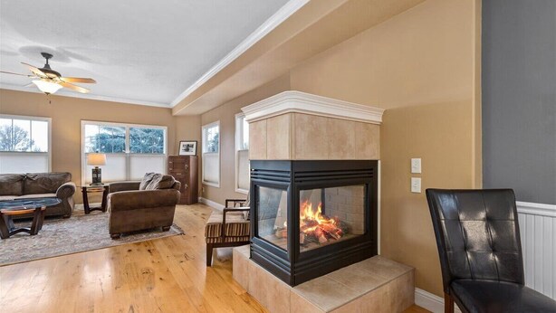 A living room with a fireplace, wooden flooring, a sofa, a coffee table, and a chair.