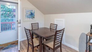 A dining area with a wooden table and four chairs, a painting on the wall, and a door leading to an outdoor balcony. - Private Loft with trail access to Boise Foothills - Pets Welcome! (Boise)