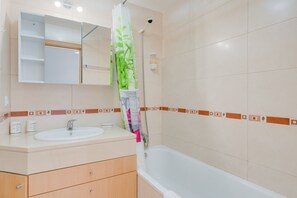 A bathroom with a sink, mirror, and shower.