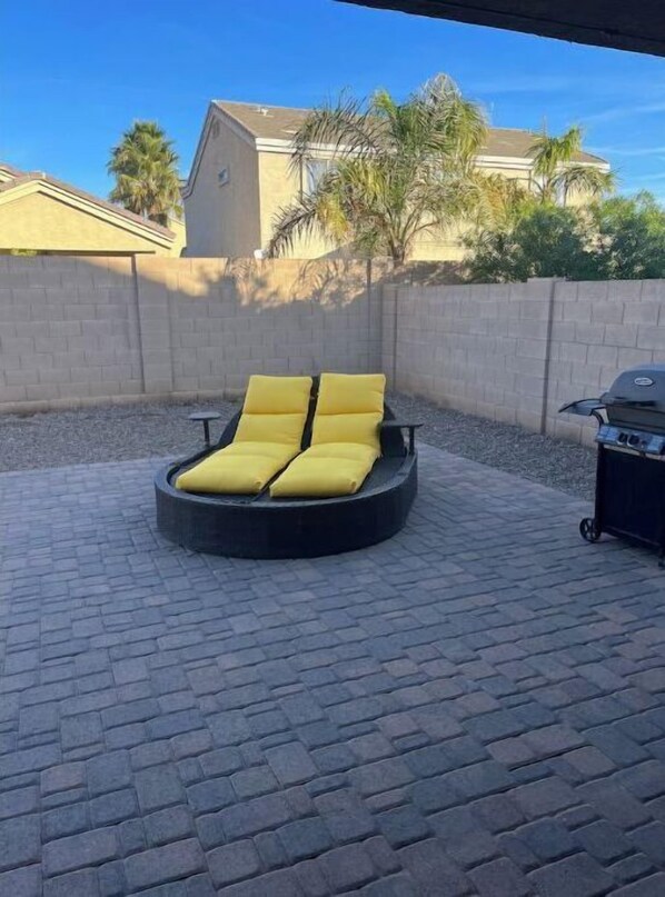 Relax in an outdoor seating area with a barbecue grill nearby.