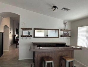 Modern kitchen with central island, shelves, and large mirror.