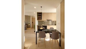 A modern kitchen with a dining table and chairs, a built-in oven, and a hanging light fixture. - Beautiful Penthouse in the Best Area of the City (Zona Calacoto La Paz)