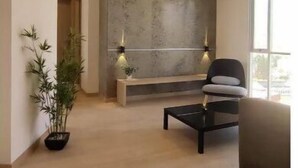 A modern living room with a wooden floor, a black sofa, a coffee table, and a large window providing natural light. - Beautiful Penthouse in the Best Area of the City (Zona Calacoto La Paz)