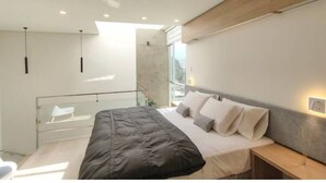 Une chambre moderne avec un grand lit, un balcon en verre et une vue sur la ville.