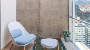 A modern balcony with a glass table and two chairs, a concrete wall, and a city view. - Beautiful Penthouse Duplex @ the best area in La Paz (Zona Calacoto La Paz)