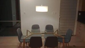 A modern dining area with a glass table and four chairs, a hanging light fixture, and a sliding door closet. - Beautiful Penthouse Duplex @ the best area in La Paz (Zona Calacoto La Paz)