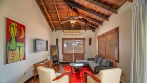 A living room with a wooden ceiling, a red rug, a sofa, two armchairs, a TV, and a painting on the wall. - Exclusive Full House near Beaches & Downtown (Roatan)